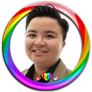 Ảnh chân dung studio chuyên nghiệp của Trang, sáng lập Trang Designs. Trang diện mặc vest beige khoác ngoài áo sơ mi đen lịch lãm phối cùng kính gọng khoan (frameless glasses) chụp trên nền xám tối giản với ánh sáng studio mềm mại